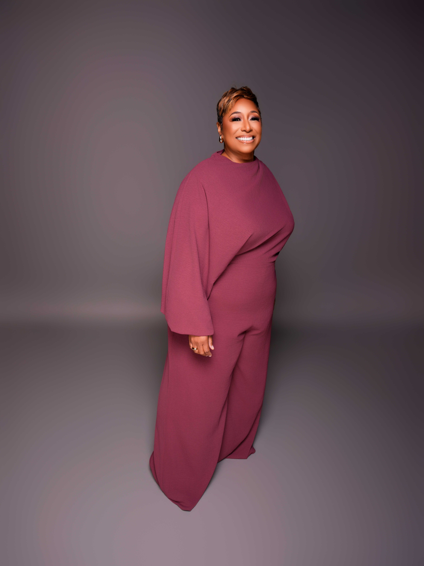 Confident executive woman leader in a deep red blazer, reflective and empowered
